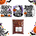 A Halloween-themed glitter bag displayed below three printed sample designs. The designs read 'Black Cat Crossing,' 'Boo Y'All,' and 'Beware Enter at Your Own Risk,' with pumpkins, ghosts, bats, and spooky graphics.